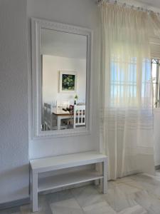 un espejo en una pared con un banco en una habitación en Apartamento Carihuela a 300 metros playa, en Torremolinos