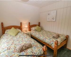 a bedroom with two beds and a lamp on a table at Tyn Lon in Aberdaron