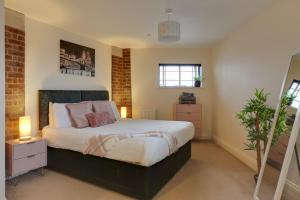 a bedroom with a bed and a brick wall at Niche Water Tower Apartments in Braintree
