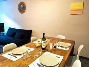 - une table en bois avec des assiettes blanches et une bouteille de vin dans l'établissement Le Bokeh - Face à la Cité Médiévale, à Carcassonne