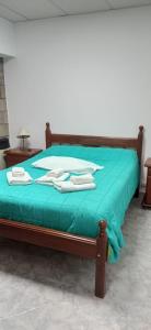 Una cama con sábanas verdes y toallas. en Look Departamentos en Carhué