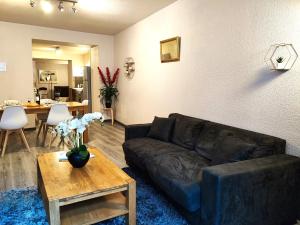 a living room with a black leather couch and a table at Le Bokeh - Face à la Cité Médiévale in Carcassonne