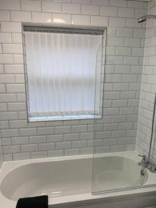 a bathroom with a tub with a window and a shower at Goodison Lodge in Liverpool