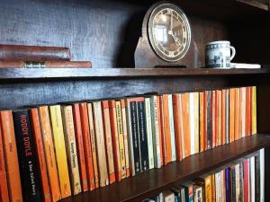 a book shelf with books and a clock on it at The Writer's House in Canterbury