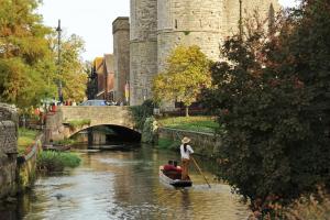 un hombre en un barco en un río con un castillo en The Writer's House en Canterbury