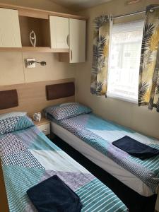 two beds in a small room with a window at Luxury Holiday Home Happiness at Tattershall lake# in Tattershall