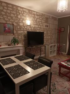 a living room with a table and a flat screen tv at La Boussole - Maison meublée 3 chambres 6 pers. in Chinon
