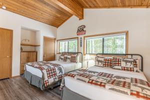 two beds in a room with wooden ceilings at Ptarmigan's Roost in Whitefish +41 photos