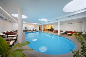 una gran piscina en un hotel con sillas y mesas en Hotel Unterrain, en Appiano sulla Strada del Vino