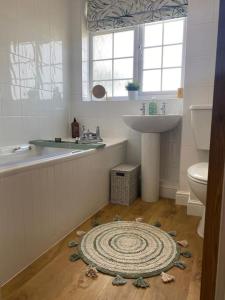 a bathroom with a sink toilet and a rug on the floor at Lotties Cottage in Broadway