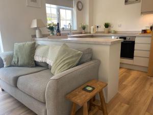 a living room with a couch and a kitchen at Lotties Cottage in Broadway