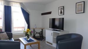 a living room with a couch and a tv at Pension Zur Mühle in Fredersdorf