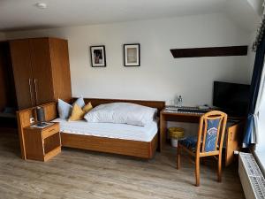 a bedroom with a bed and a desk and a television at Pension Zur Mühle 