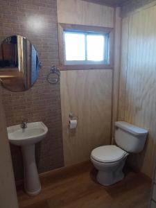 ein Bad mit einem WC, einem Waschbecken und einem Fenster in der Unterkunft Peumayen in Quellón
