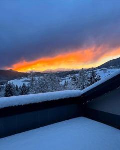 una vista su un tramonto da un balcone con neve di Attico con vista AltopianoAsiago a Roana