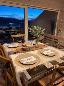 un tavolo da pranzo con sedie e una grande finestra di Attico con vista AltopianoAsiago a Roana