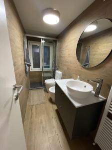 a bathroom with a sink and a toilet and a mirror at Attico con vista AltopianoAsiago in Roana