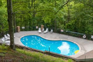 a blue swimming pool in the middle of a forest at Real Log Cabin With Amazing Views, Hot Tub, Sauna, Games in Gatlinburg