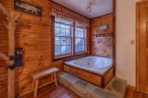 Habitación con paredes de madera y baño con bañera. en Real Log Cabin With Amazing Views, Hot Tub, Sauna, Games, en Gatlinburg