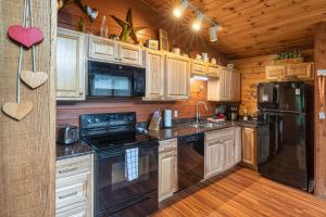 a kitchen with wooden cabinets and a black refrigerator at Real Log Cabin With Amazing Views, Hot Tub, Sauna, Games in Gatlinburg