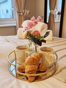 ein Tablett mit Croissants und Tassen Kaffee auf dem Bett in der Unterkunft Home from Home Slough in Slough