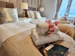 een hotelkamer met 2 bedden met handdoeken en bloemen bij Home from Home Slough in Slough