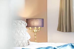 a lamp sitting next to a bed in a bedroom at Aylesbury House with Free Parking, Super-Fast Wifi and Smart TV with Netflix by Yoko Property in Aylesbury