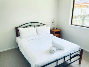 ein Bett mit weißer Bettwäsche und einem Handtuch darauf in der Unterkunft Peaceful 2 Bedroom Home in Wagga Wagga