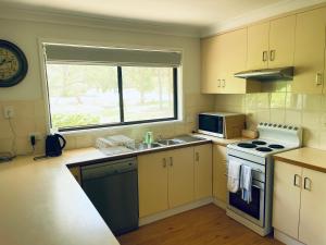 eine Küche mit einer Spüle, einem Herd und einem Fenster in der Unterkunft Peaceful 2 Bedroom Home in Wagga Wagga