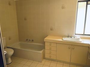 a bathroom with a tub and a sink and a toilet at Peaceful 2 Bedroom Home in Wagga Wagga