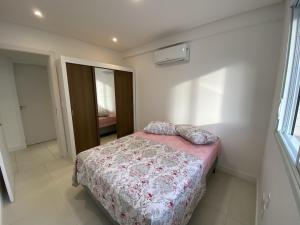 1 dormitorio con 1 cama con manta rosa y almohadas en Apartamento em Torres-906 - Uma quadra do mar, en Torres