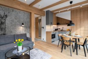 a living room and kitchen with a couch and a table at REST4U APARTAMENTY z SAUNAMI in Szczyrk