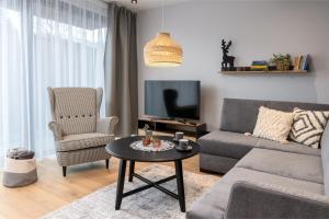 a living room with a couch and a table and a tv at REST4U APARTAMENTY z SAUNAMI in Szczyrk