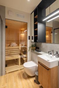 a bathroom with a tub and a toilet and a sink at REST4U APARTAMENTY z SAUNAMI in Szczyrk