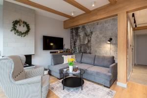 Una sala de estar con un sofá y un televisor en REST4U APARTAMENTY z SAUNAMI, en Szczyrk
