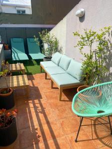 eine Terrasse mit einem blauen Sofa, Stühlen und Pflanzen in der Unterkunft Cruz Apartments in Lissabon