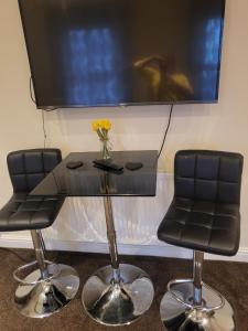 two chairs and a table with a tv on a wall at Exclusive apartment in Bristol in Bristol