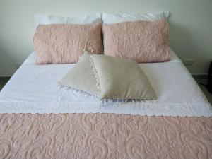 Cama con sábanas y almohadas rosas y blancas en Apartamento vista a la montaña, en Girardot
