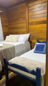 2 camas en una habitación con paredes de madera en Casa Sempre Viva, en Caraíva