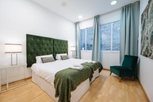 a bedroom with a large bed and a green headboard at HomeySeville-Amazing Views Cathedral Tomas de Ibarra - 8 pax, Parking Optional in Seville