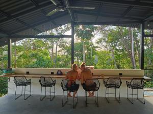 two women sitting on chairs at a bar at Shipwrecked Hostel in Uvita