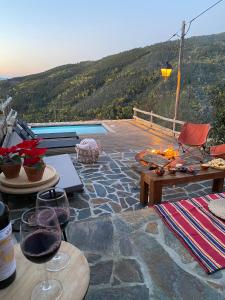 eine Terrasse mit einem Tisch, Stühlen und einem Pool in der Unterkunft Casa do Ti Tóte in Talasnal
