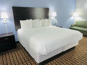 a bedroom with a large bed and a chair at Days Inn by Wyndham, Glen Allen - Richmond North in Richmond