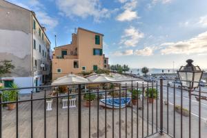 濱海里約的住宿－Appartamento per 4 sul mare a Rio Marina, Elba，建筑前带椅子和遮阳伞的围栏