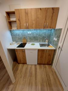 Elle comprend une petite cuisine avec un évier et des placards en bois. dans l'établissement Dolly Zlatibor, à Zlatibor