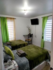 two beds in a room with green curtains and a television at Downtown apartment next to highway netflix+wifi in Edmundston