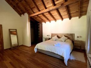 1 dormitorio con cama blanca y techo de madera en Casa en San Martin de Los Andes en San Martín de los Andes