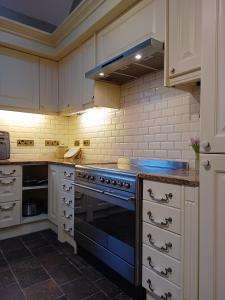 a kitchen with a blue stove and white cabinets at The West Wing at Eriviat Hall Hot Tub in Henllan