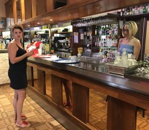 a woman standing at a counter in a bar at Hotel de Paris in Le Bugue
