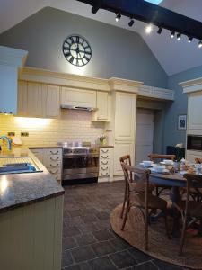 a kitchen with a table and a clock on the wall at The West Wing at Eriviat Hall Hot Tub in Henllan